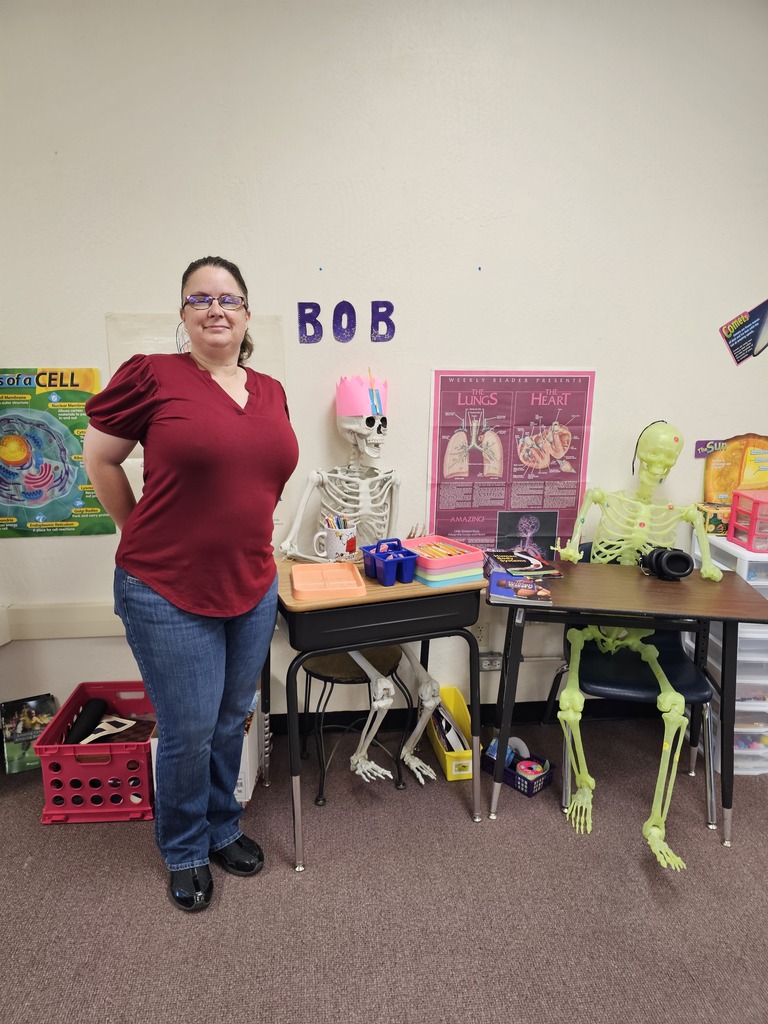 Mrs. Fischer in her classroom with two skeletons named Bob and Bertha.
