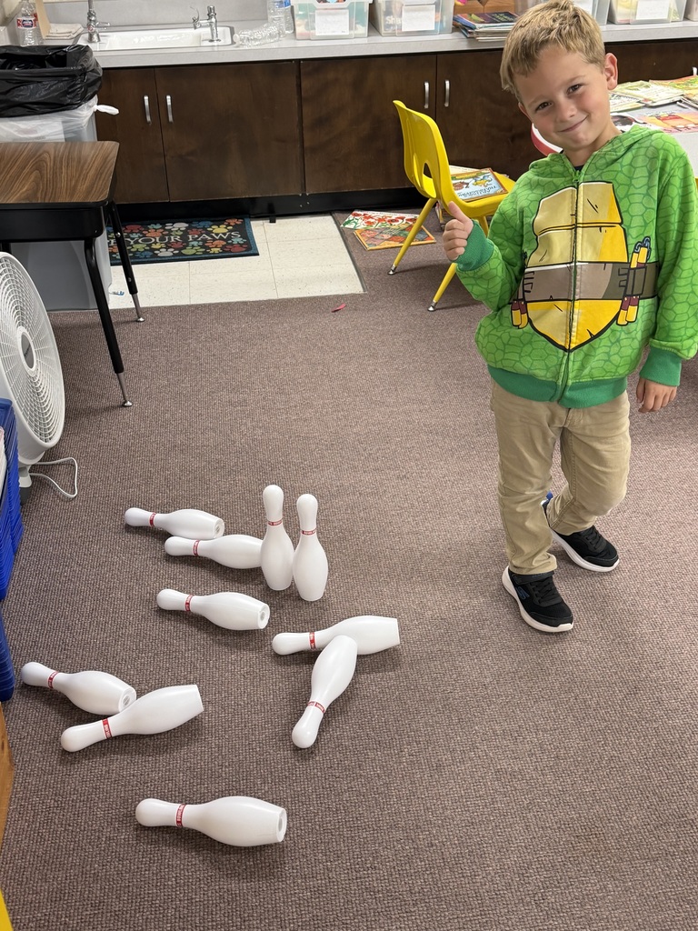 First grade boy showing a thumbs up next to bowling pins.