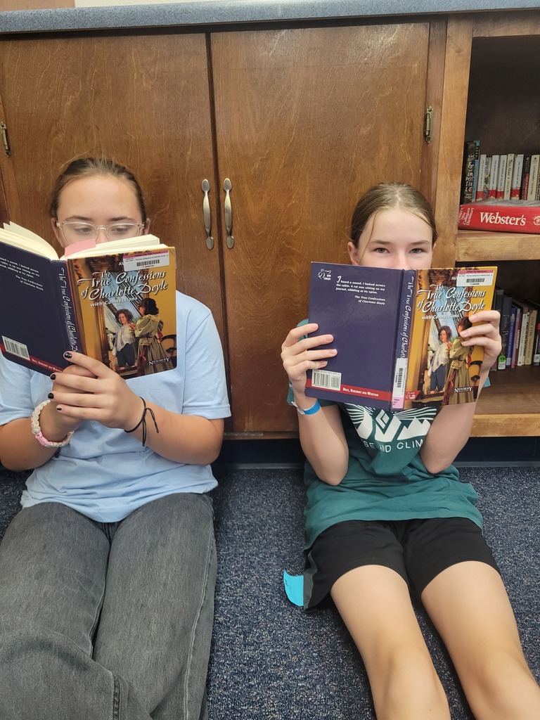 Two students read The True Confessions of Charlotte Doyle together.