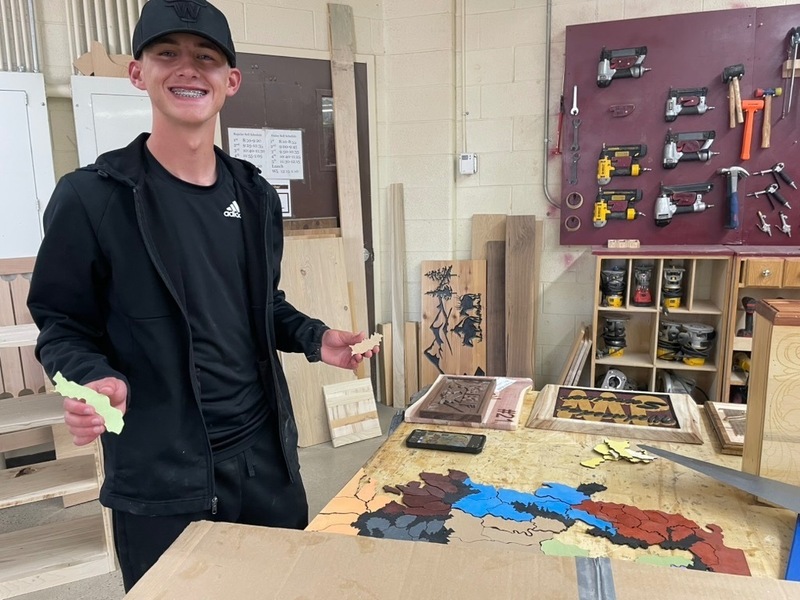 Brody Kjar displays his CNC-created game board project inspired by the landscape and world of The Lord of the Rings, combining digital design and woodworking.