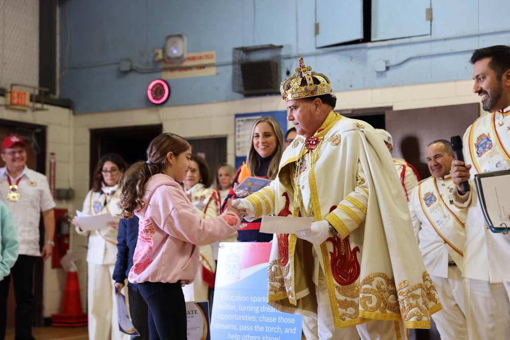 Man in a crown and king costume shaking hands with a girl.