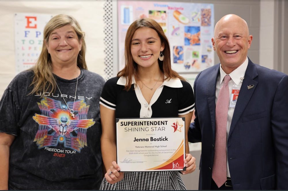 Student holding certificate standing with the principal and superintendent.