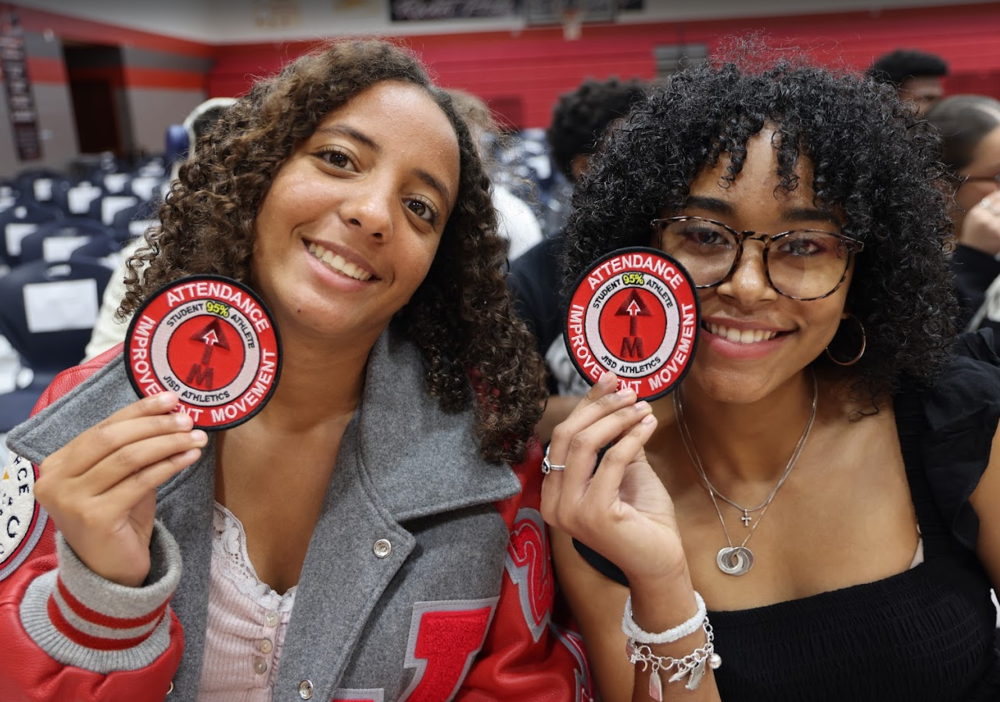 Two students holding patches about attendance.