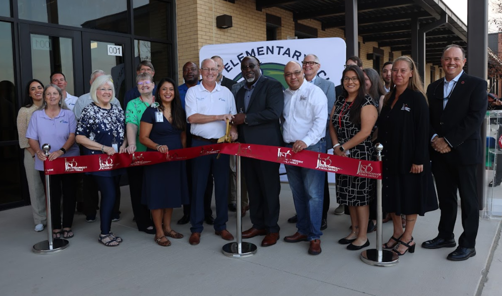 People standing behind a red ribbon with ceremonial scissors