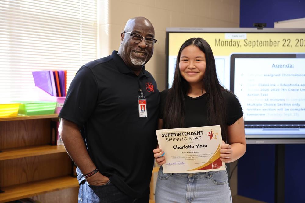 Man standing with student receiving an award.
