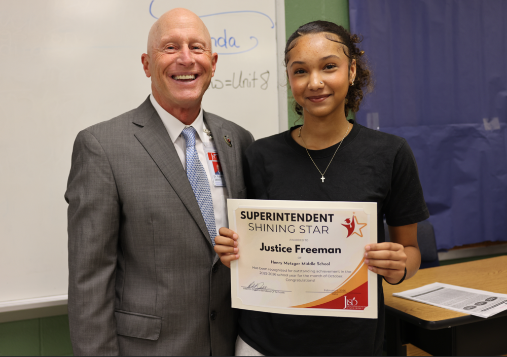 Man in gray suit with student holding a Superintendent Shining Star Certificate