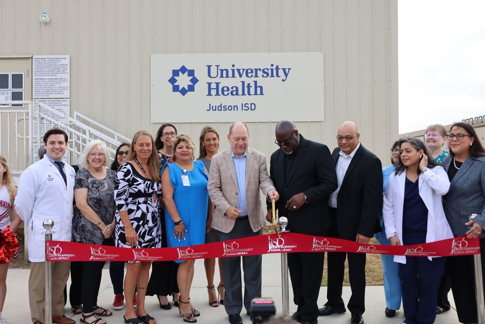 People standing in front of a ribbon with ceremonial scissors