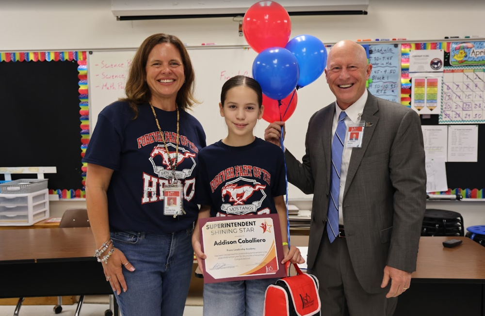 Lady and man standing with a student holding an award.