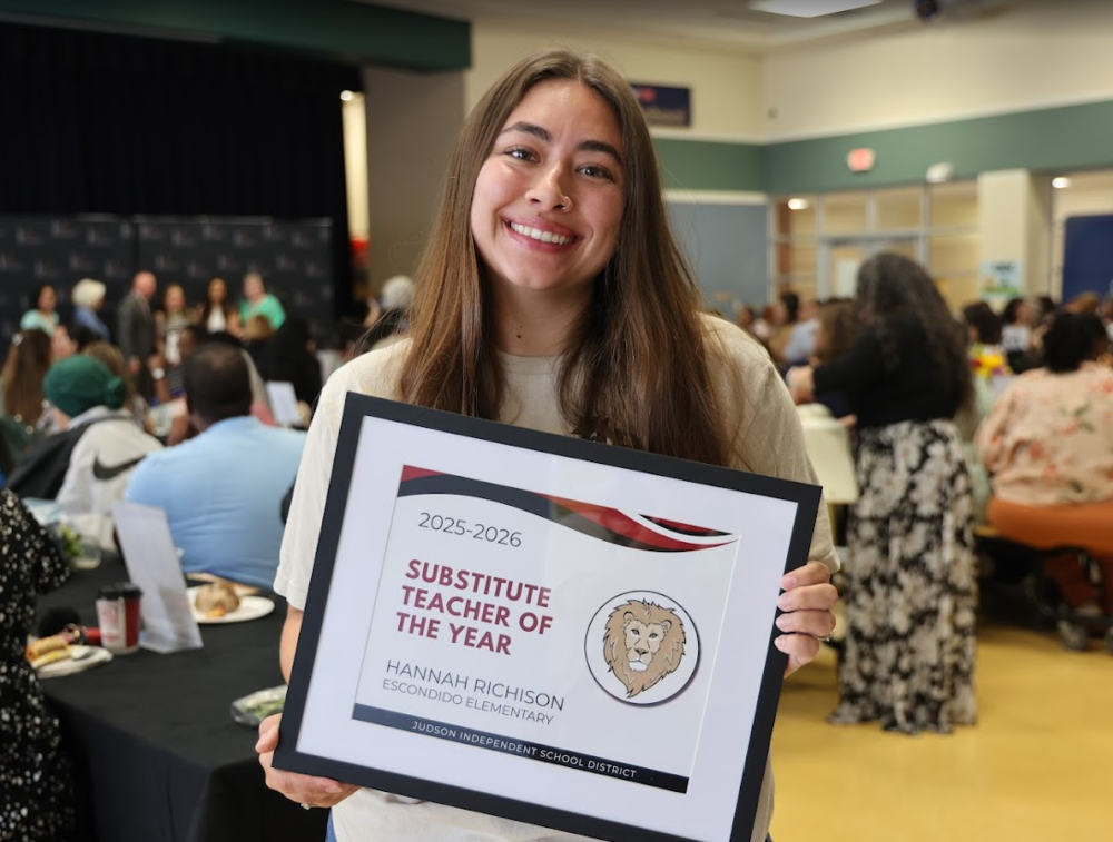 Woman smiling holding a substitute teacher of the year award.
