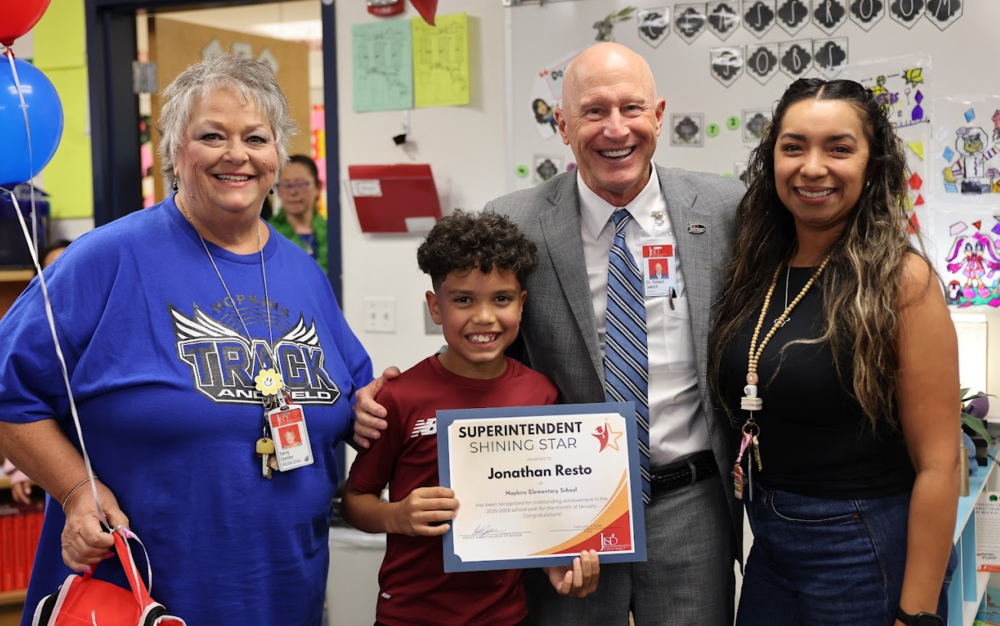 Three adults standing with a student who is holding an award.