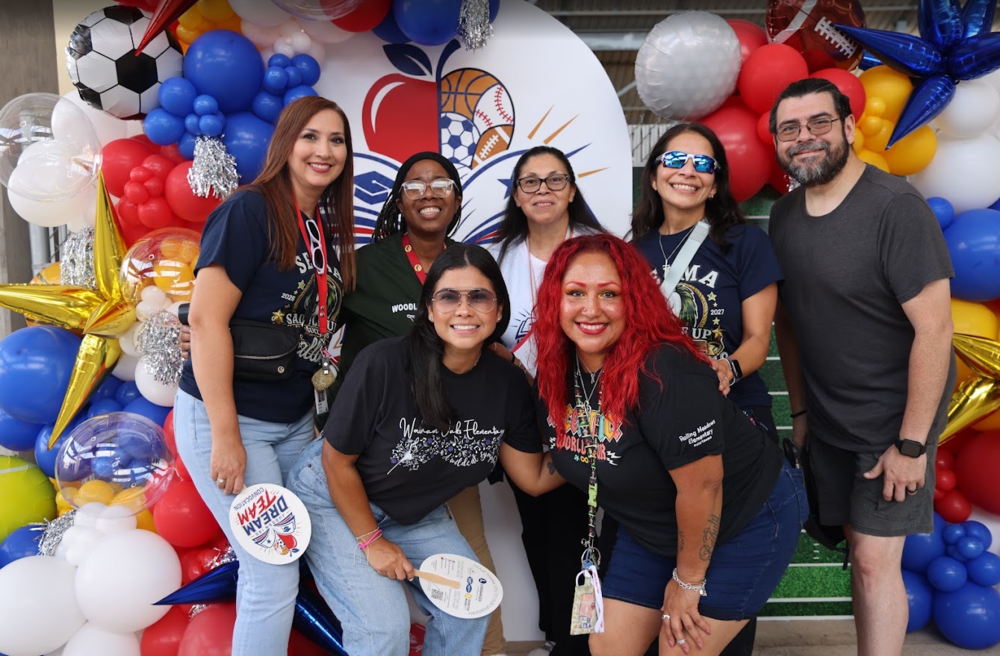 People standing in front of balloons smiling.
