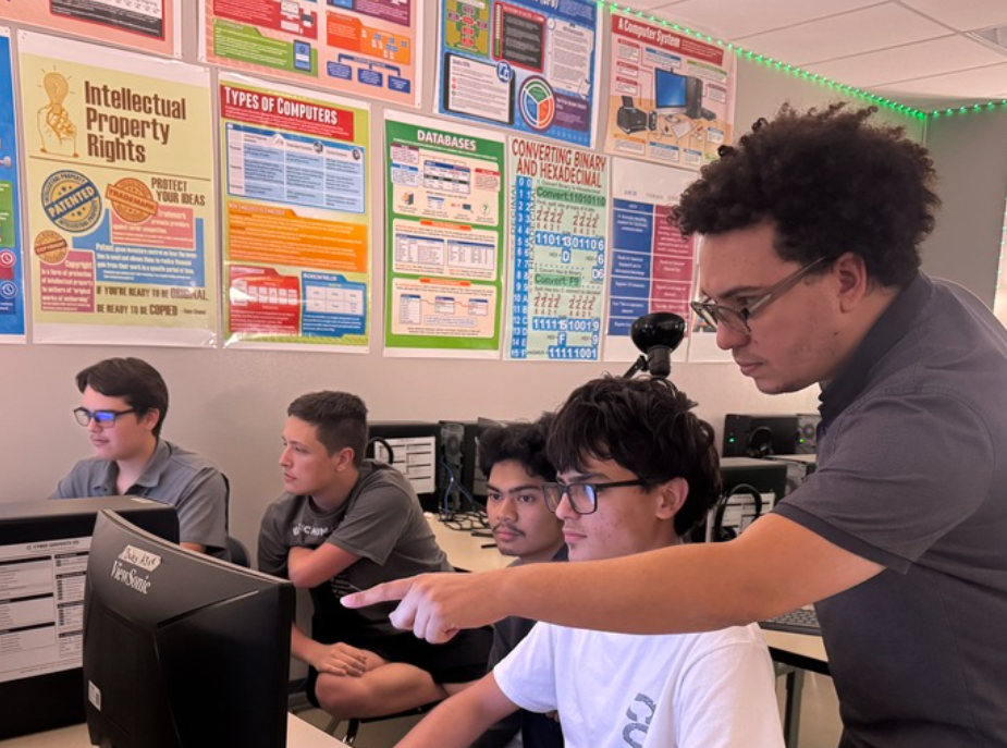 Three students and their instructor in the Cyber Security classroom