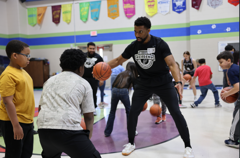 Man with basketball teaching students.