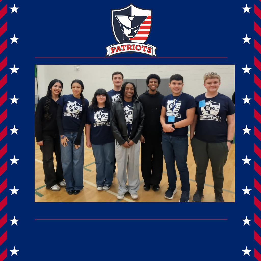 Group of Veterans Memorial High School robotics students wearing team shirts and smiling inside a gym after competition.
