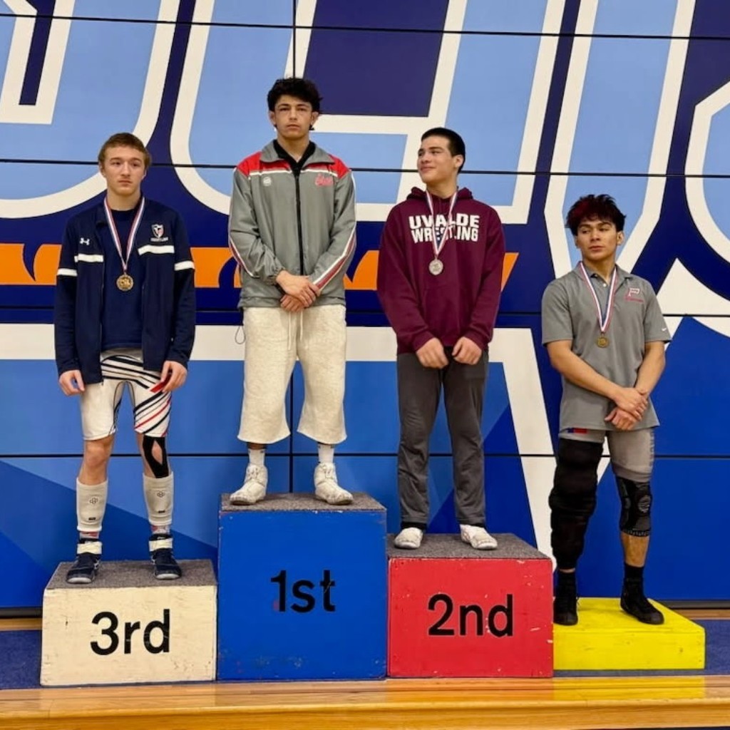 Male student wrestlers on podium receiving awards