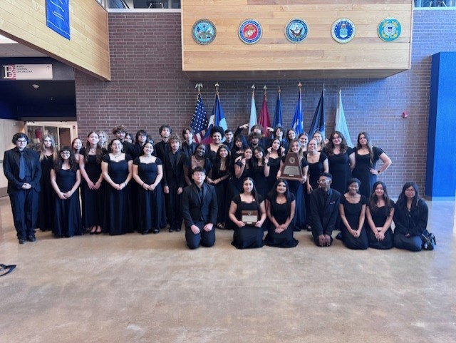Orchestra students posing in their competition dress with their awards