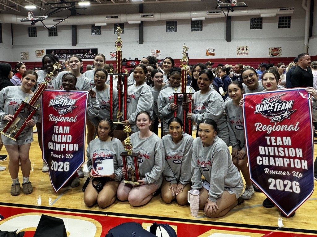 Dance team posing in the contest gym with their banners and trophies