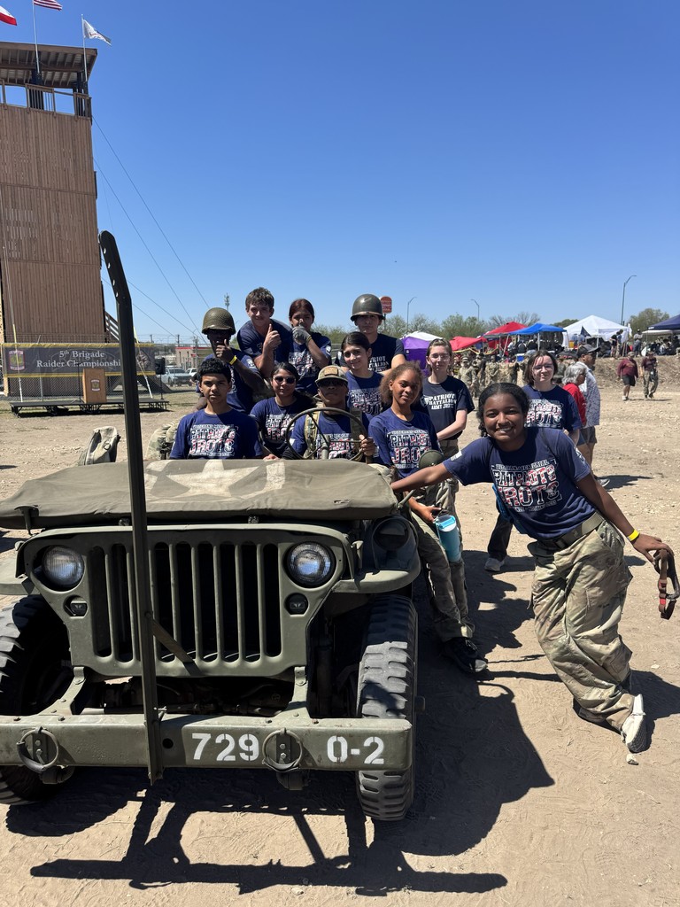 JROTC cadets pose with a vintage  military vehicle 