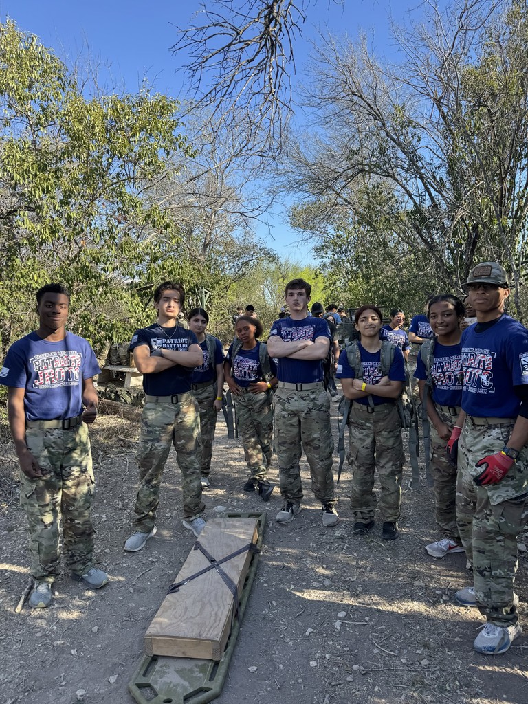 JROTC students pose in half circle with a weighted backboard on the ground