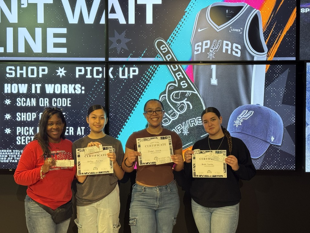 JROTC instructor Sgt Hudson poses with three of the all-female colorguard with their certificates and Spurs game tickets 