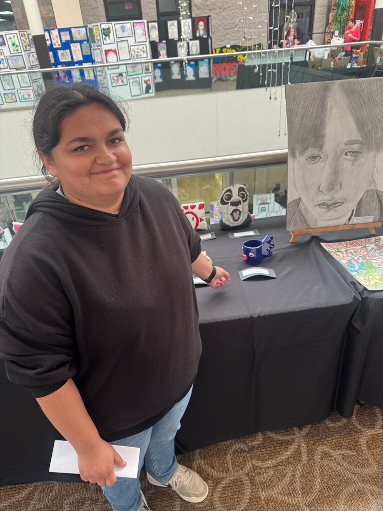 Student stands with artwork