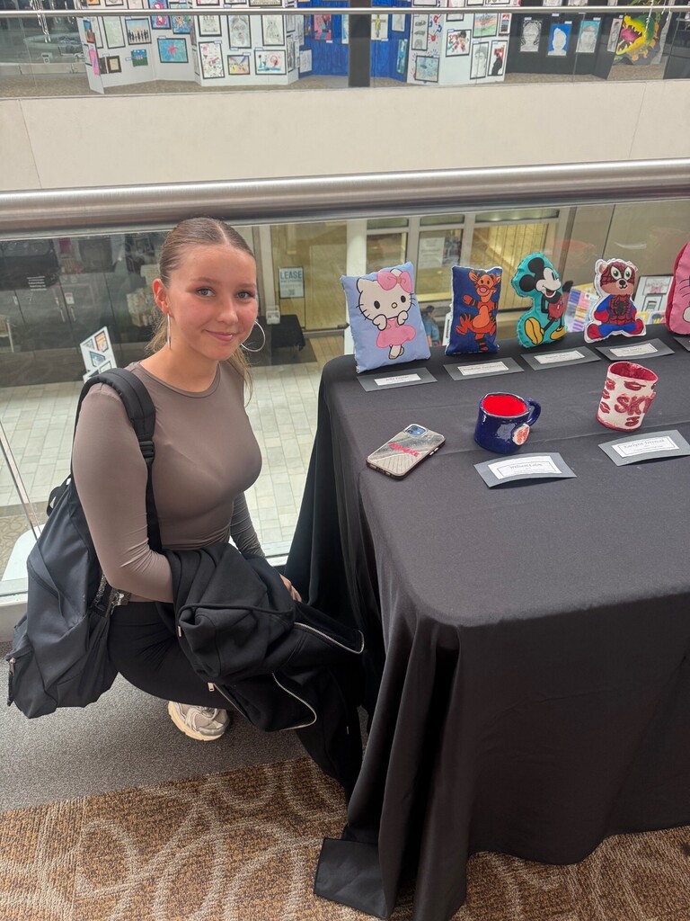Student kneels with artwork
