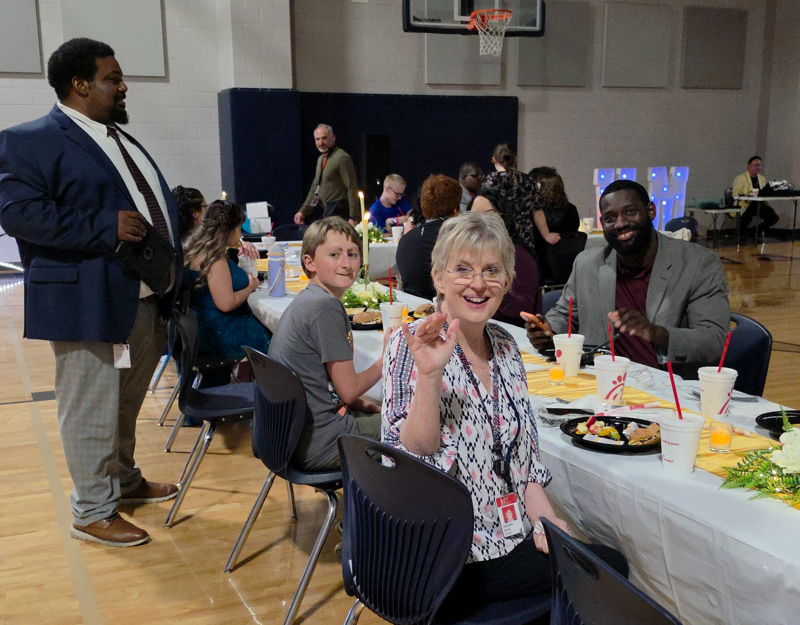Paraprofessional Jacky Davis and other staff sitting at the dining tables enjoying Chick-fill-a catering