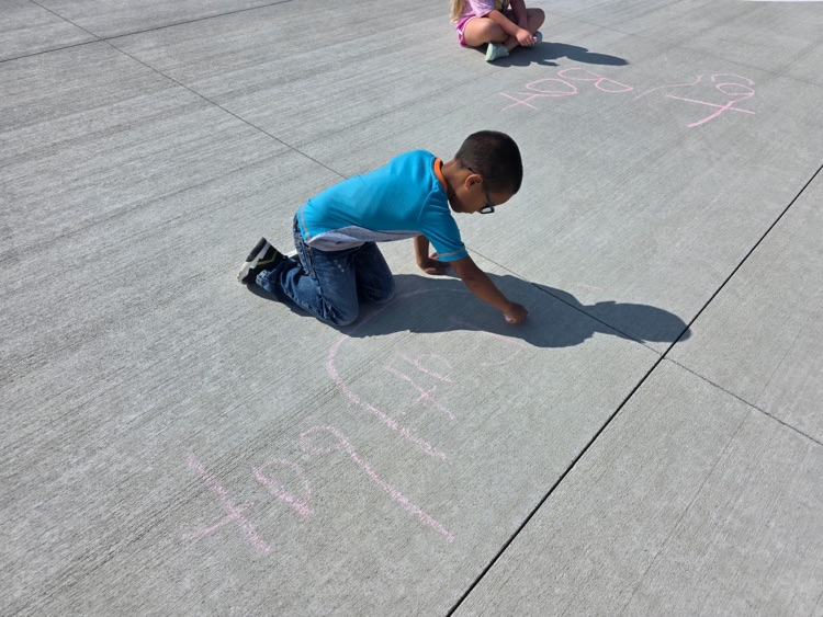 Practicing spelling words with sidewalk chalk.