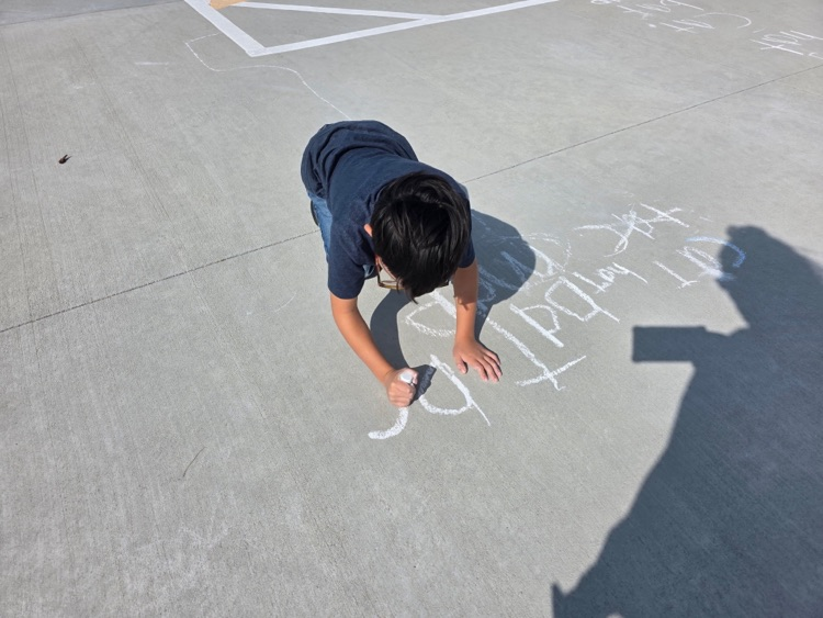 Practicing spelling words with sidewalk chalk.