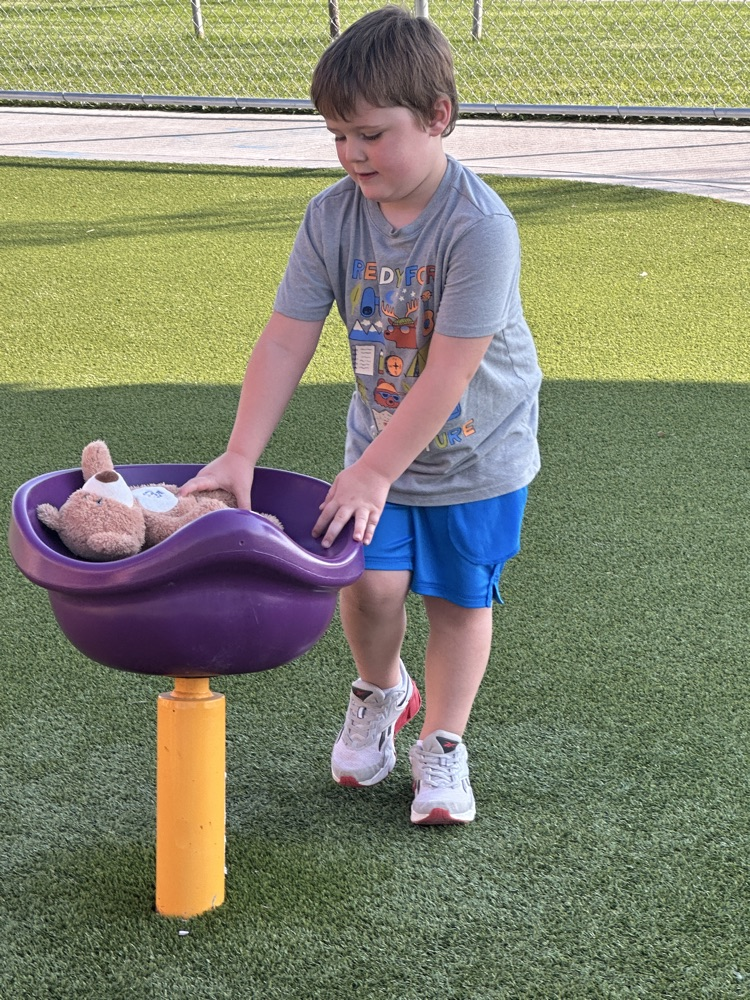 a boy spinning teddy bear in playground spinning cup