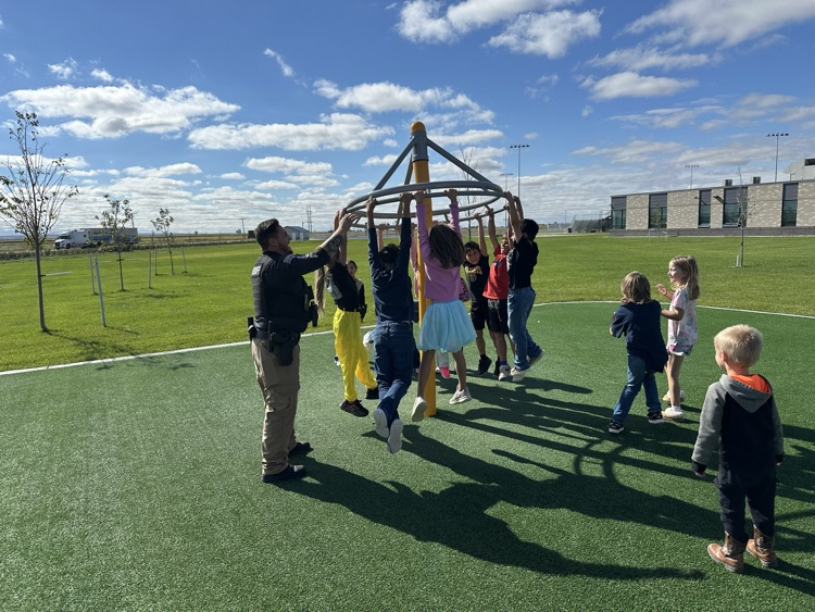 Deputy Clark pushing students on the playground.