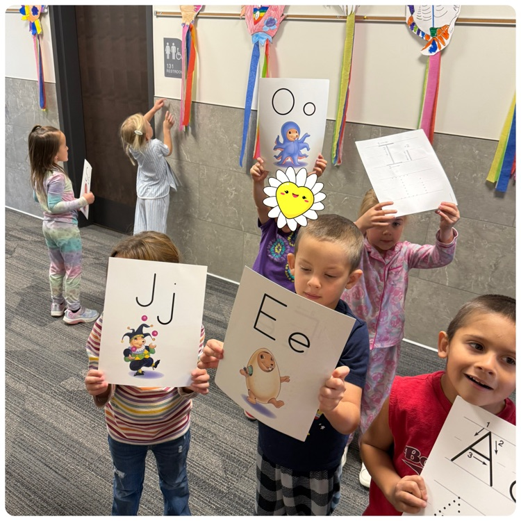 students showing their alphabet flashcards during a letter hunt throughout the school