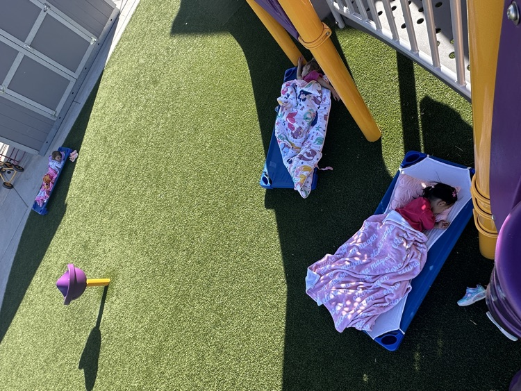 preschool students laying on their mats outside on the playground for nap time 