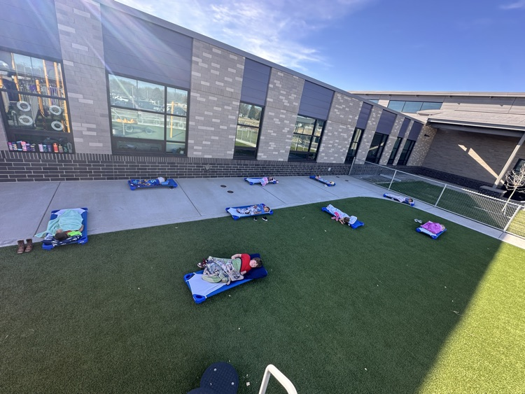 preschool students laying on their mats outside on the playground for nap time 