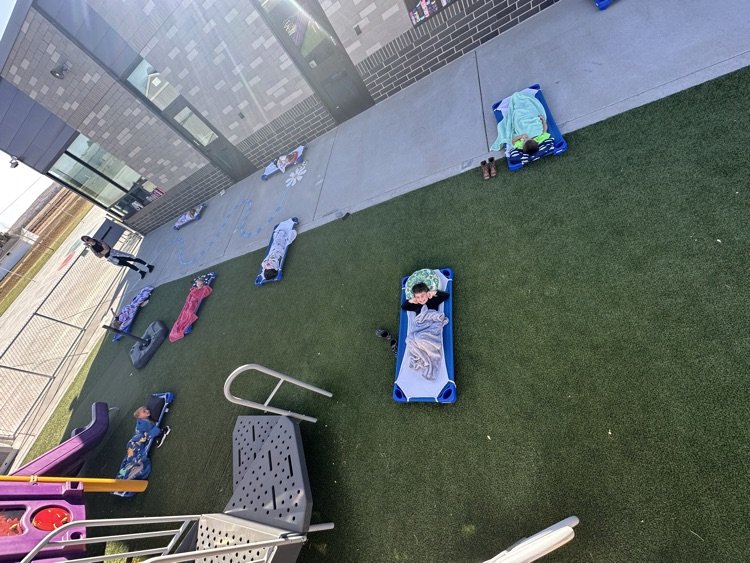preschool students laying on their mats outside on the playground for nap time 