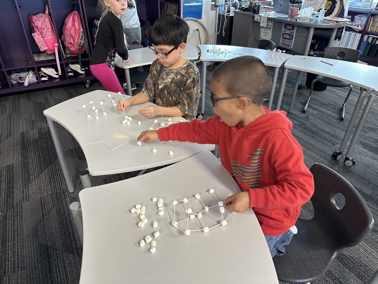 First graders using marshmallows and toothpicks to build 3D shapes in math class  