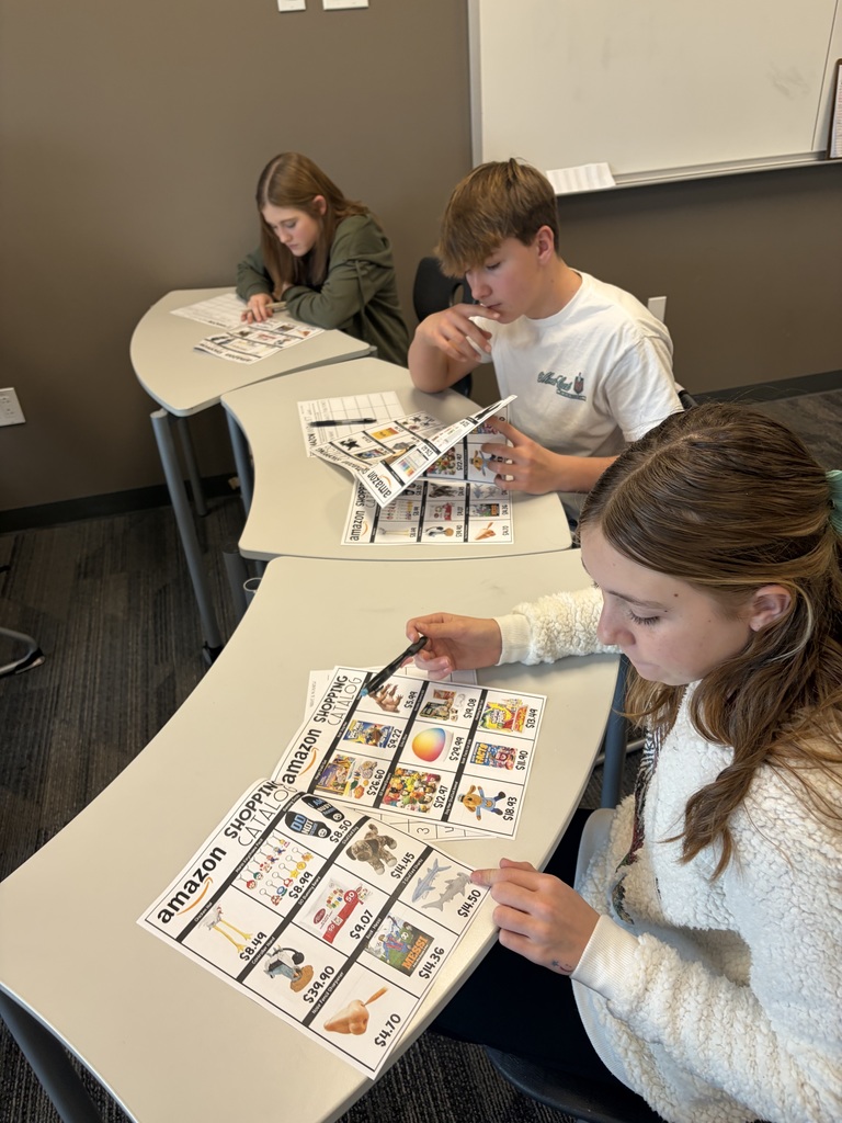 studnets looking through a catalog as they look for their top 10 items to shop! SO MANY DECISIONS TO MAKE!