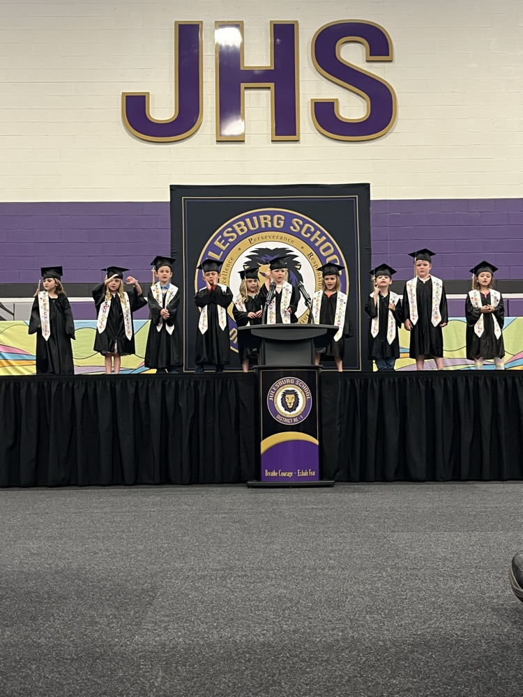 students on stage for preschool graduation. students in caps and gowns