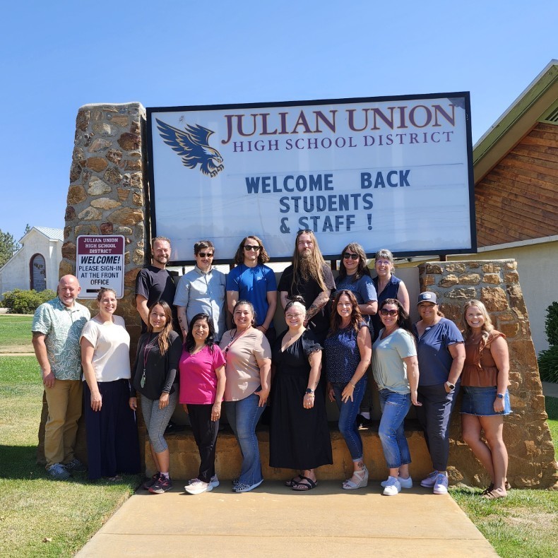 JHS staff members pose in front of marquee with "Welcome back students & staff".