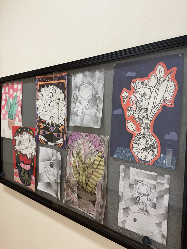 A bulletin board displays various art pieces. The artwork includes flowers, plants, and abstract designs.