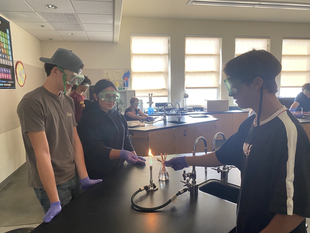 Three students observe during a chemistry experiment with fire.