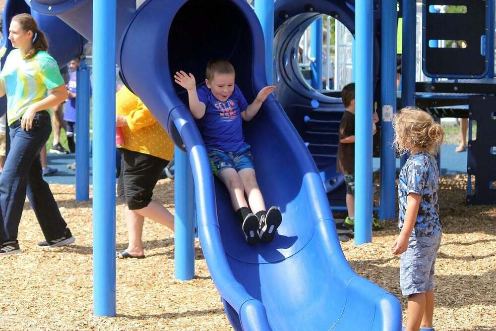 child on slide with friend watching