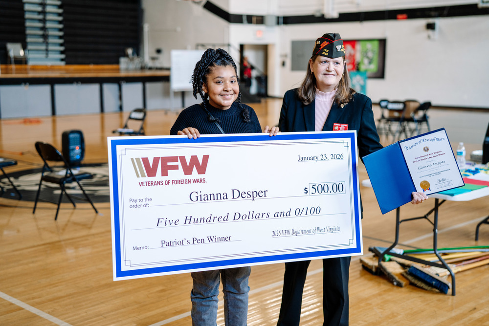 Gianna smiling at the camera, while holding her oversized check for 500 dollars that she got for winning the state title.