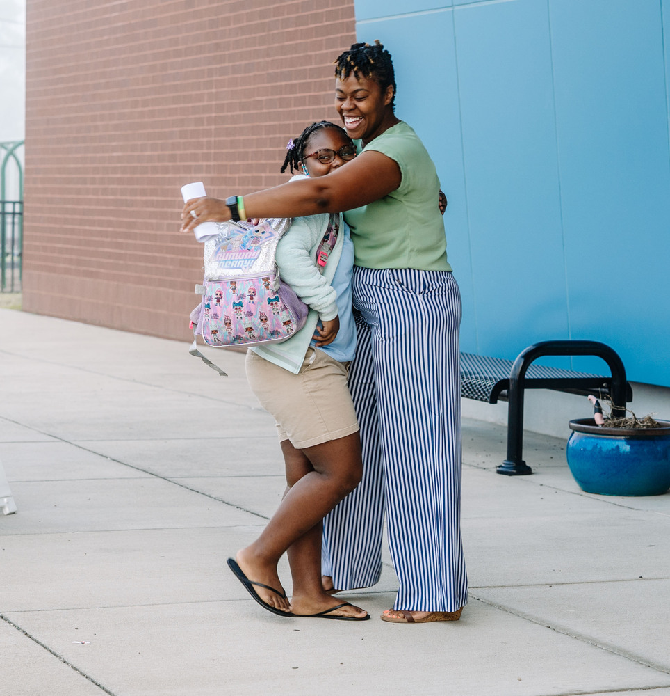 principal and student hugging each other outside of the school.