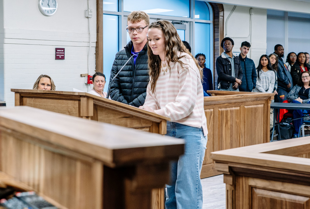KCS Student leadership team co-presidents standing at the podium in the KCS Board Room reading the group's goals to board members.