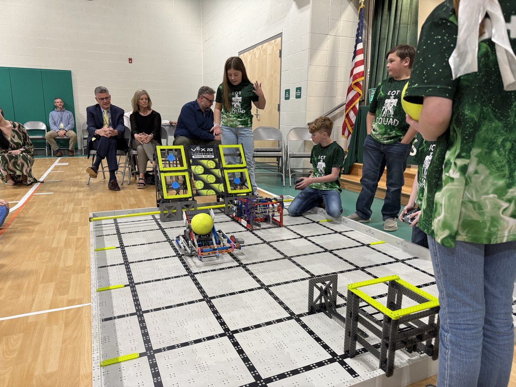 the bot squad practicing with their robots in the school gym