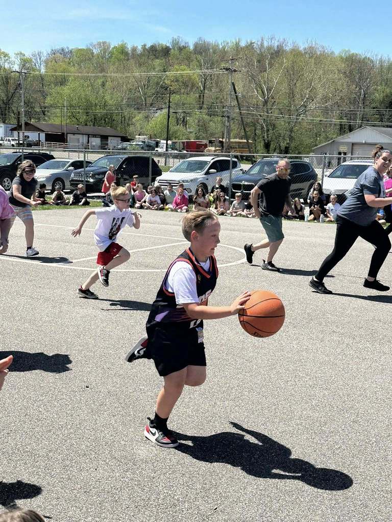 student dribbling the ball up the court during the student vs. staff basketball game. 