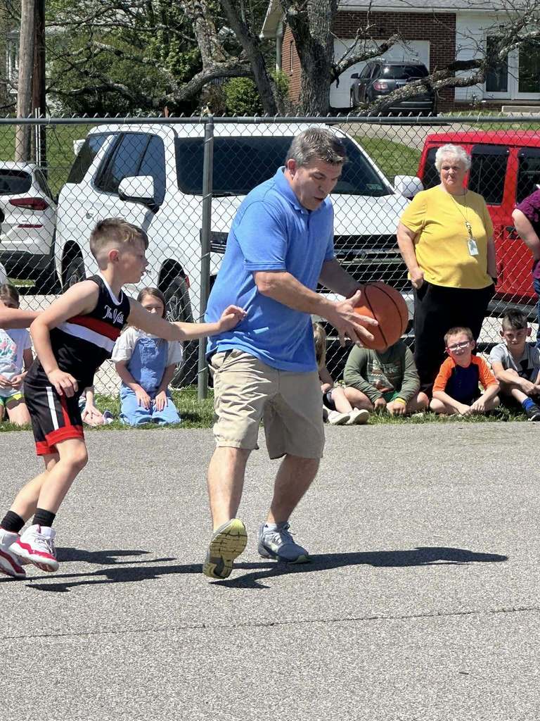 staff member dribbling the ball while a student is guarding him. 