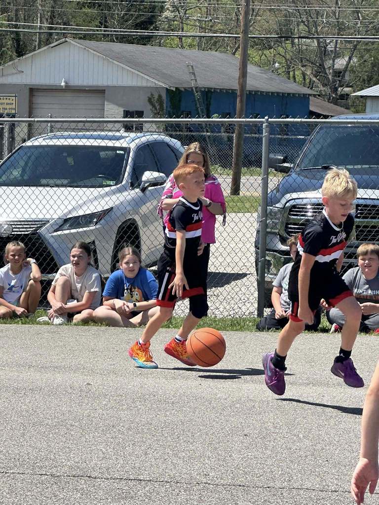 student dribbling the ball up the court during the student vs. staff basketball game. 