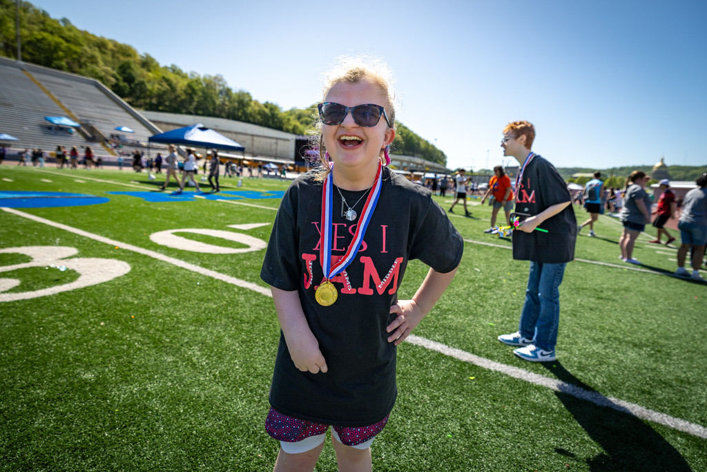 a young girl showing off her medal from the exceptional spring games. 